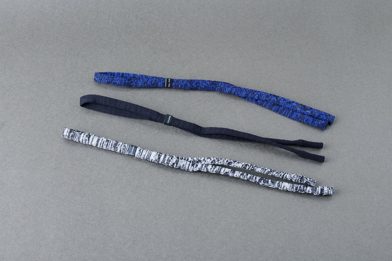 Two blue and black striped headbands on a gray background